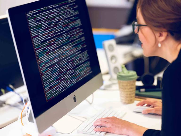A female developer gazes at code on an iMac